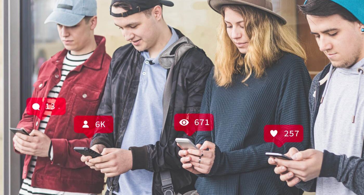 Four young people standing beside each other on cell phones - Common Unity: The Best Way to Find It in the Age of AI