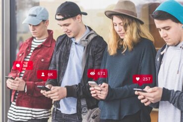 Four young people standing beside each other on cell phones - Common Unity: The Best Way to Find It in the Age of AI