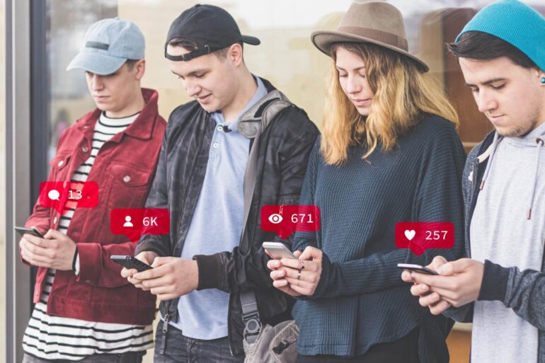 Four young people standing beside each other on cell phones - Common Unity: The Best Way to Find It in the Age of AI