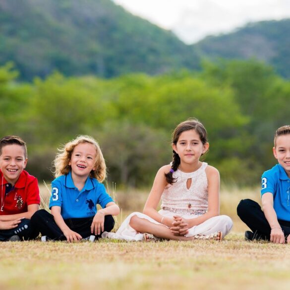 Four happy young kids sitting on ground outdoors - Positive Psychology: Why It’s So Important for Kids
