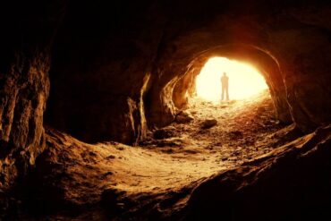Silhouette of man standing at illuminated opening of cave - Create Your Own Meaningful Grief Ritual in 3 Stages