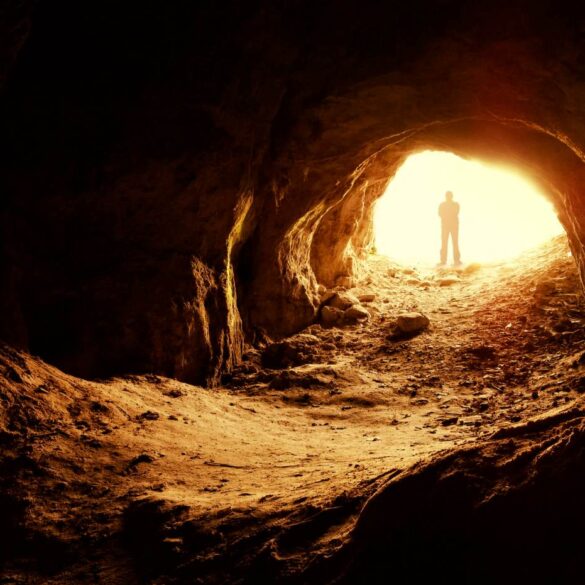 Silhouette of man standing at illuminated opening of cave - Create Your Own Meaningful Grief Ritual in 3 Stages