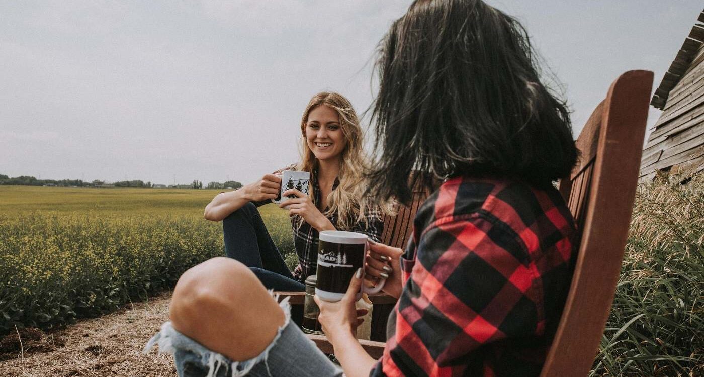 Two young female friends drinking coffee on chairs outdoors - Healthy Self-Alignment: How Mindfulness Can Lead You There