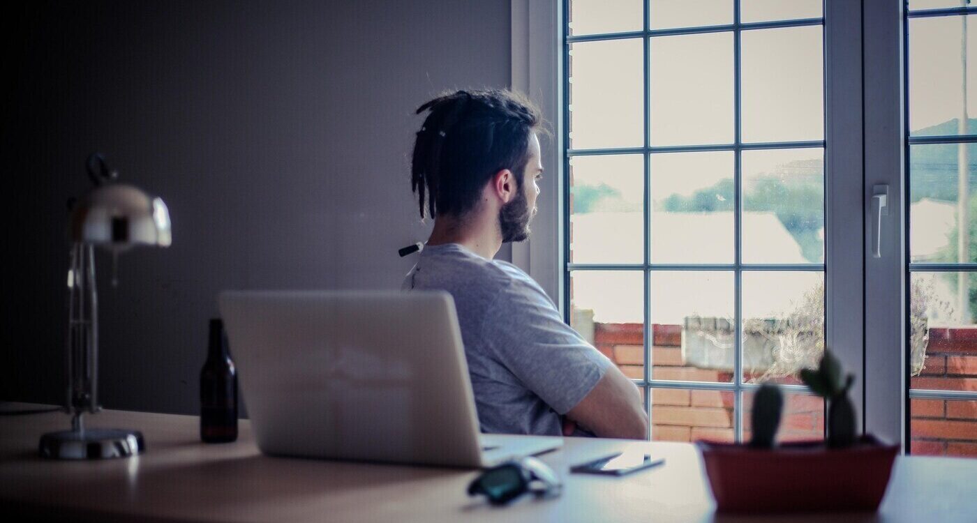 Man relaxing and looking out window while sitting at office desk - Why Mindfulness Matters Greatly in the Modern Workplace