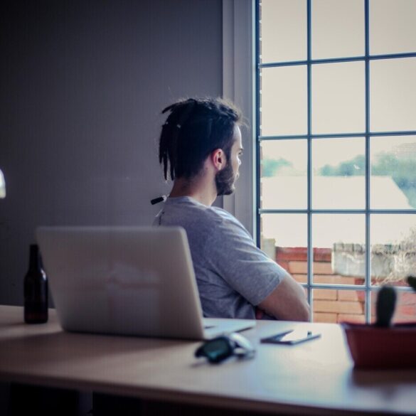 Man relaxing and looking out window while sitting at office desk - Why Mindfulness Matters Greatly in the Modern Workplace