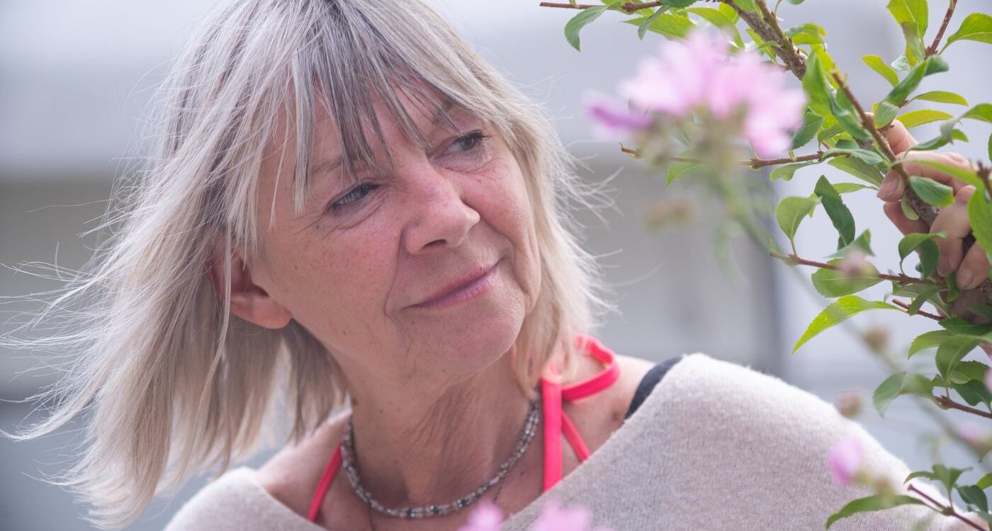 Senior woman reaching out and peacefully touching plant - Try a Simple 3 Moments of Joy Exercise to Cultivate Optimism