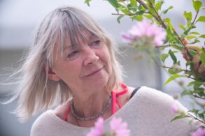 Senior woman reaching out and peacefully touching plant - Try a Simple 3 Moments of Joy Exercise to Cultivate Optimism
