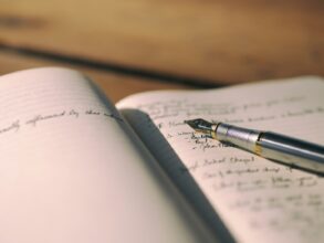 Pen resting on white lined notebook with writing in it - 6 Important Ways Writing Helps People Emotionally