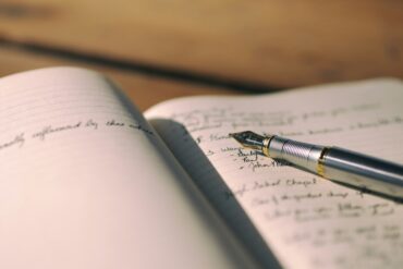 Pen resting on white lined notebook with writing in it - 6 Important Ways Writing Helps People Emotionally