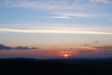 Clouds with silver lining and sun in distance - Finding the Silver Lining When Life Breaks You Open