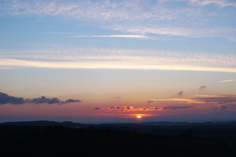 Clouds with silver lining and sun in distance - Finding the Silver Lining When Life Breaks You Open