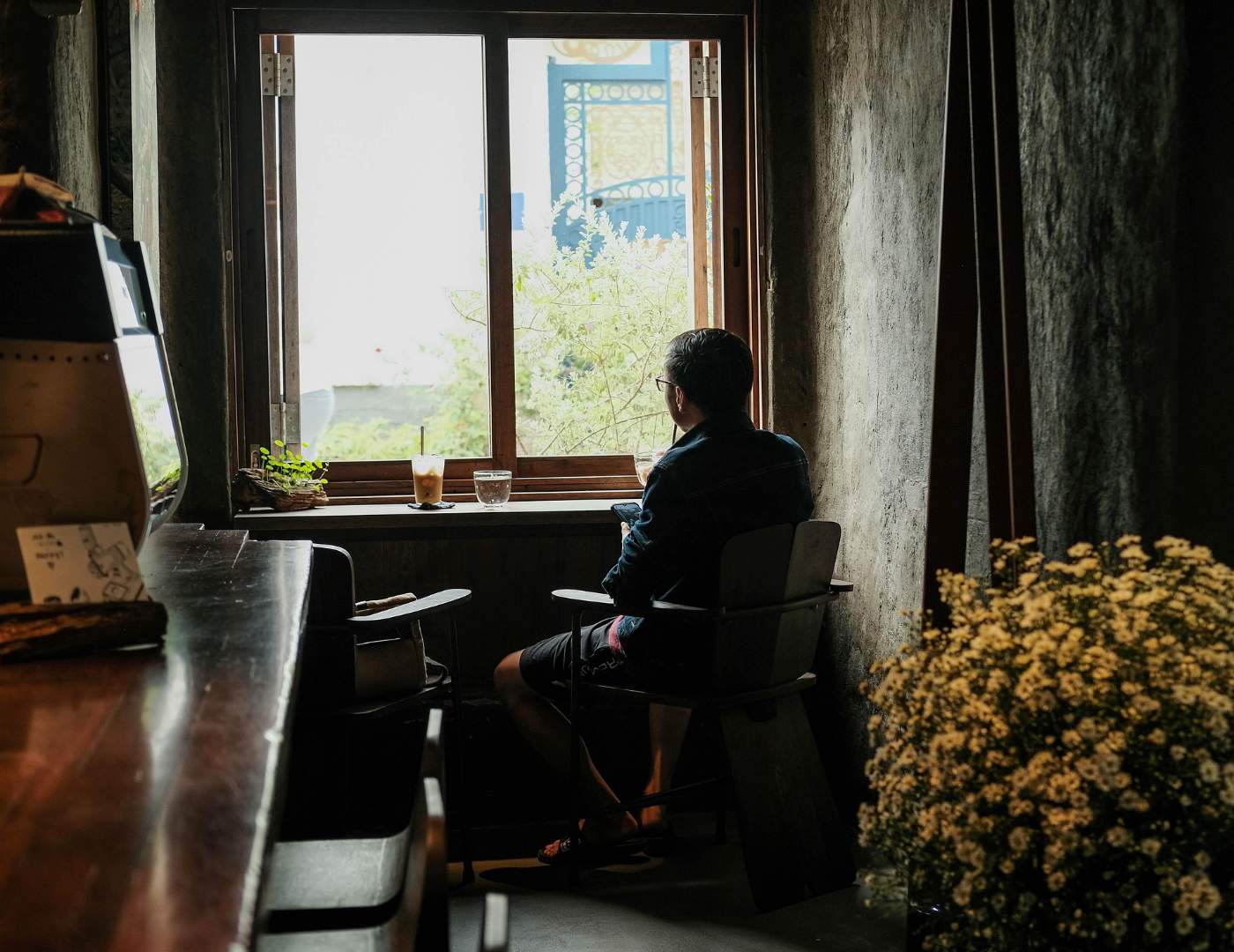 THE QUIET POWER OF DOING LESS: Finding peace in a culture of constant doing 13 Person looking out window with water and coffee beside them - The Quiet Power of Doing Less Amid a Busy World