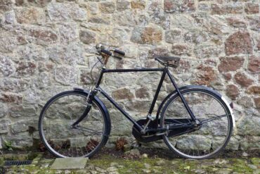 Traditional bicycle parked outdoors against stone wall - "Creepy Creatures" and 4 More New Poems About Life’s Seasons